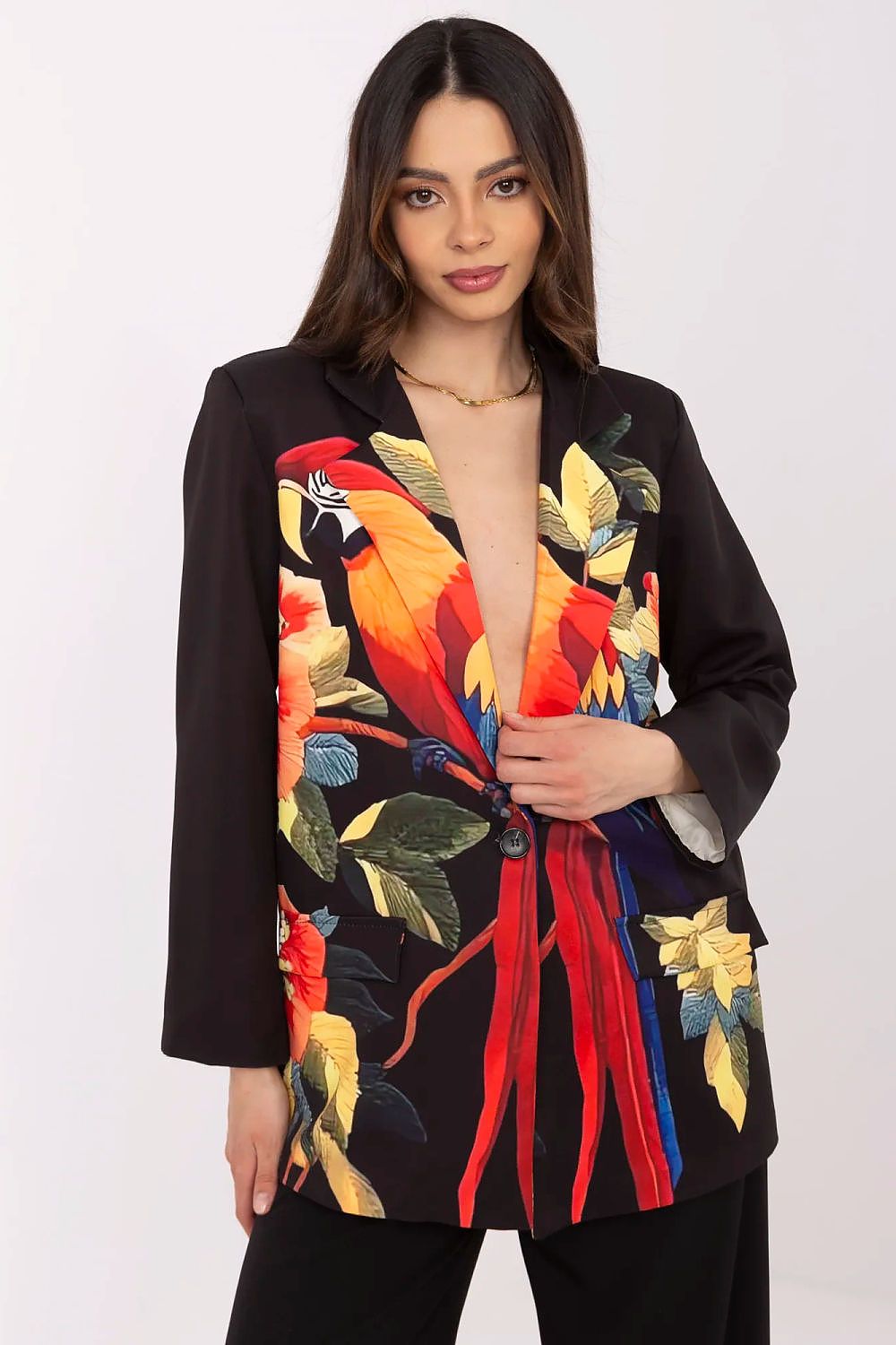Woman wearing a black blazer with colorful parrot embroidery on a white background