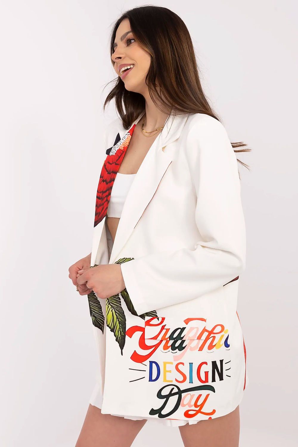 Woman wearing a white blazer with colorful text and floral design on a plain background