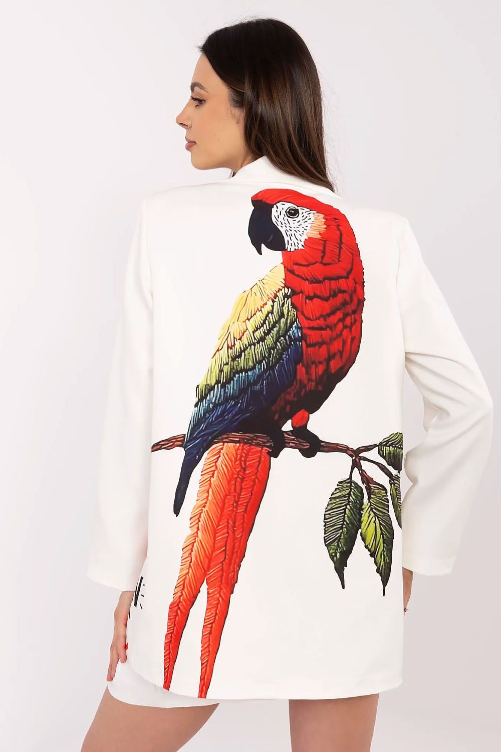 Woman wearing a white sweater with a colorful parrot design on a plain background