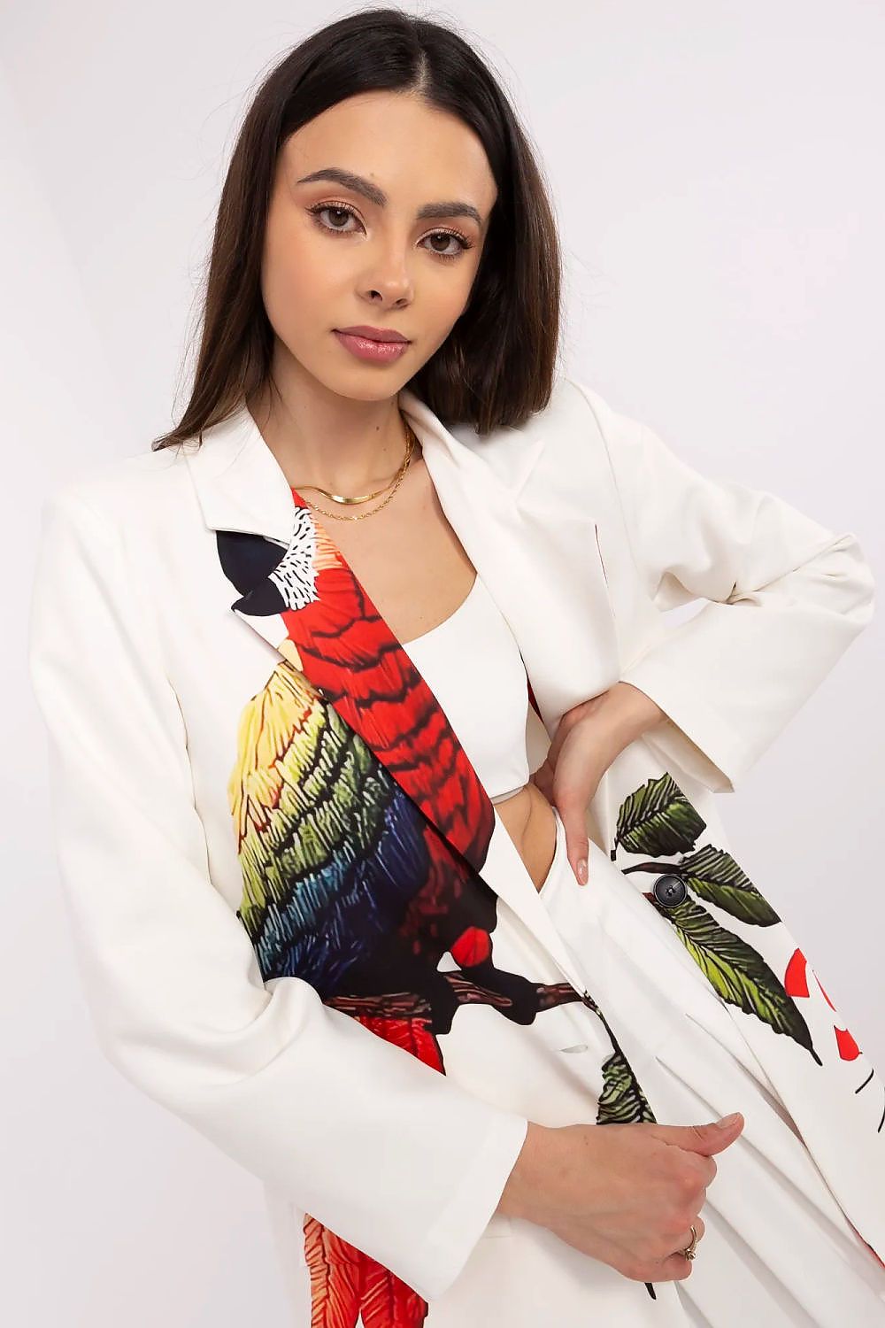 Woman wearing a white blazer with colorful parrot design on a white background