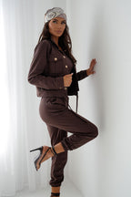 Woman in a brown outfit posing against a white curtain