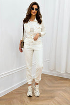Woman in a white outfit standing in a room with white walls and wooden flooring.
