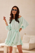 Woman wearing a light green off-shoulder dress indoors.
