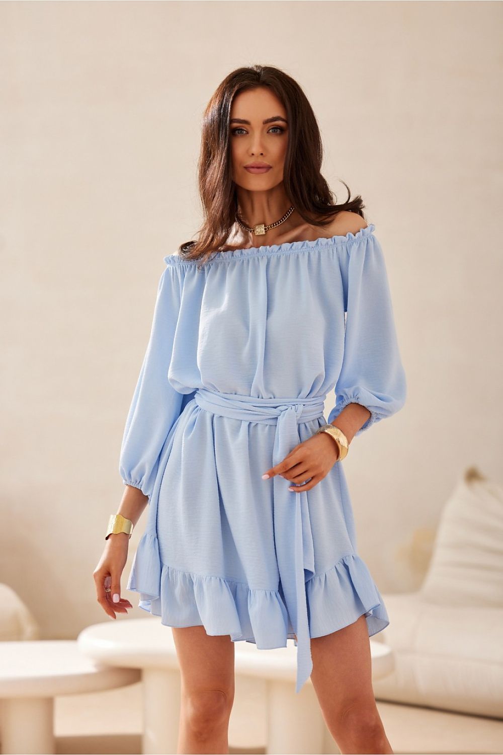 Woman wearing a light blue off-shoulder dress in an indoor setting