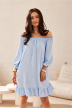 Woman wearing a light blue off-shoulder dress in a neutral setting