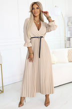 Woman wearing a beige pleated dress in a bright room.