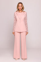 Woman wearing a pink suit with lace sleeves on a light pink background