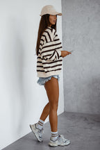 Person wearing a striped sweater and cap, standing against a plain wall.