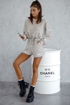 Woman in striped outfit standing next to a Chanel barrel.