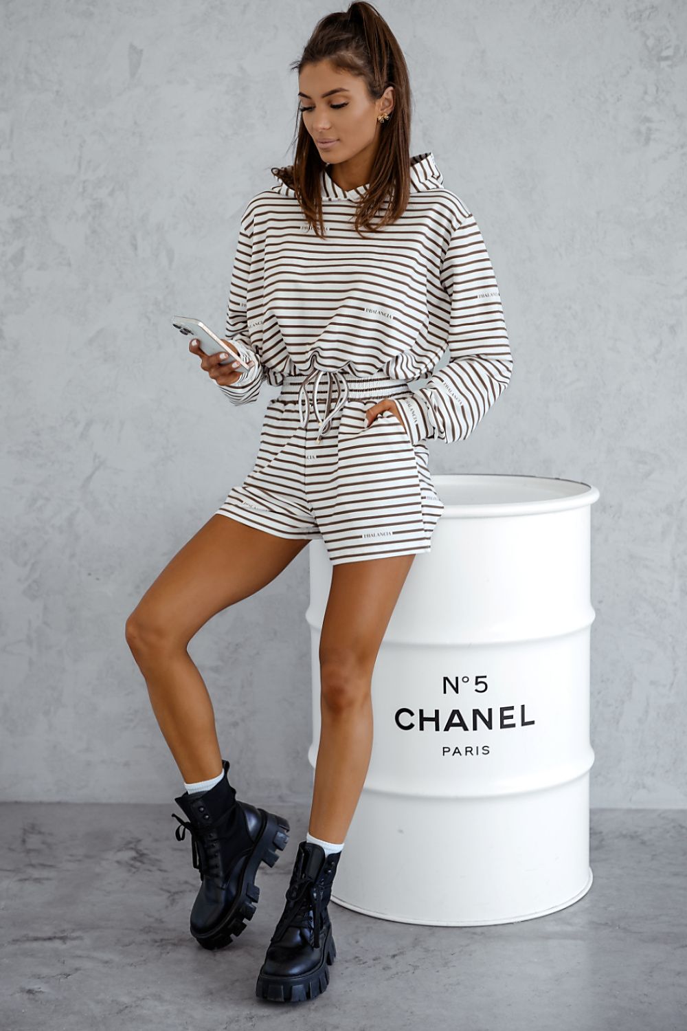 Woman in striped outfit standing next to a Chanel barrel.