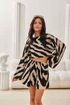 Woman wearing a zebra print outfit in a minimalistic room.