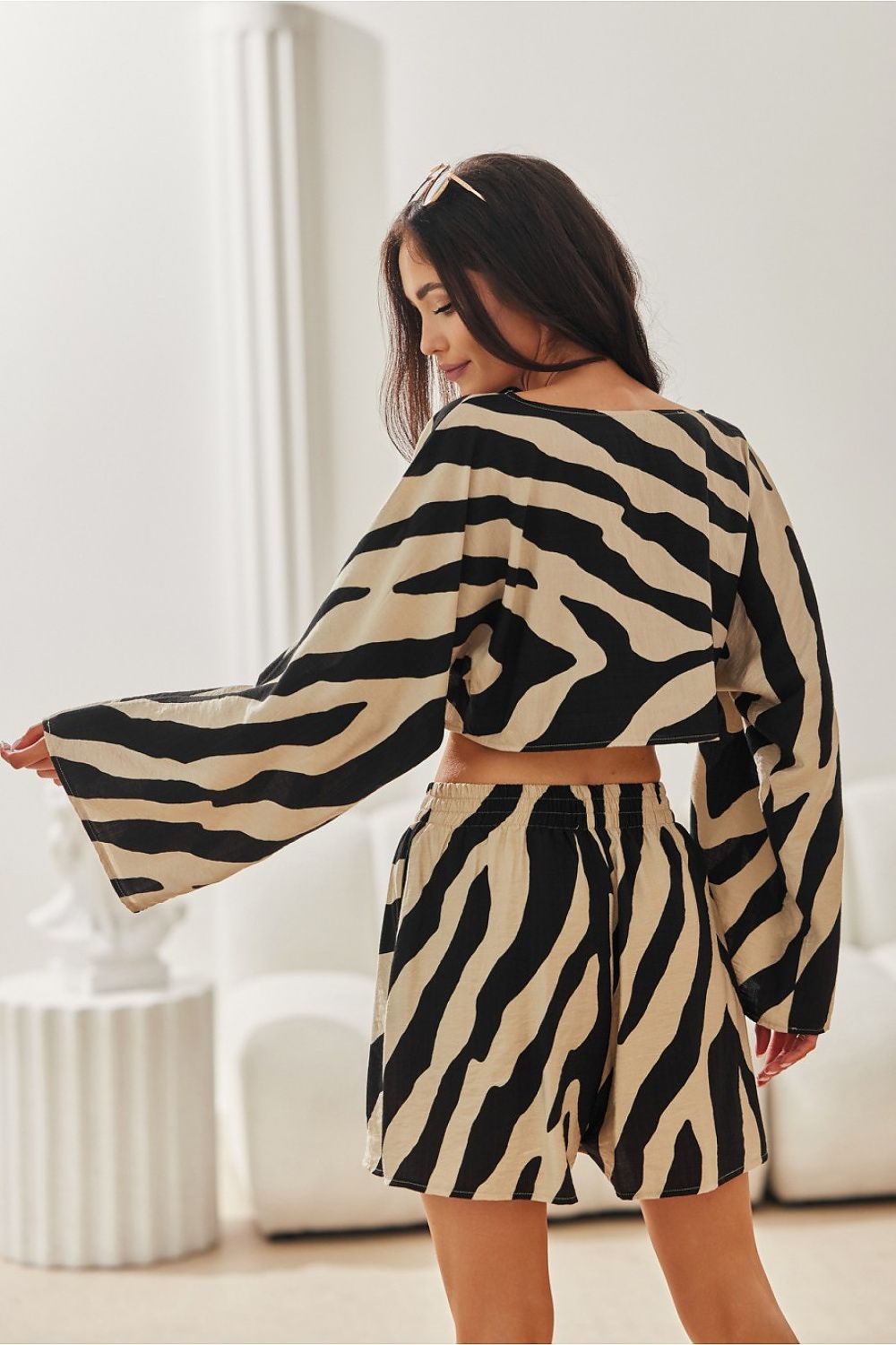 Woman wearing a zebra print outfit in a minimalistic room.