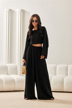 Woman in a black outfit standing in a modern living room.
