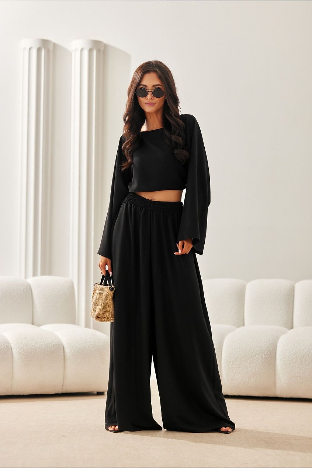 Woman in a black outfit standing in a modern living room.