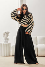Woman wearing a zebra print top and black wide-leg pants in a modern living room.