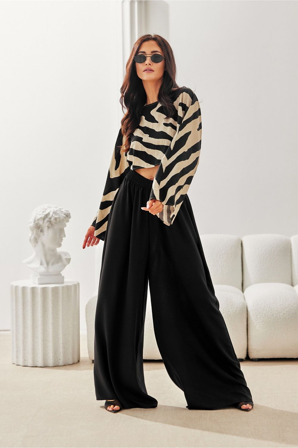 Woman wearing a zebra print top and black pants in a modern living room.