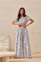Woman wearing a patterned outfit standing against a beige background