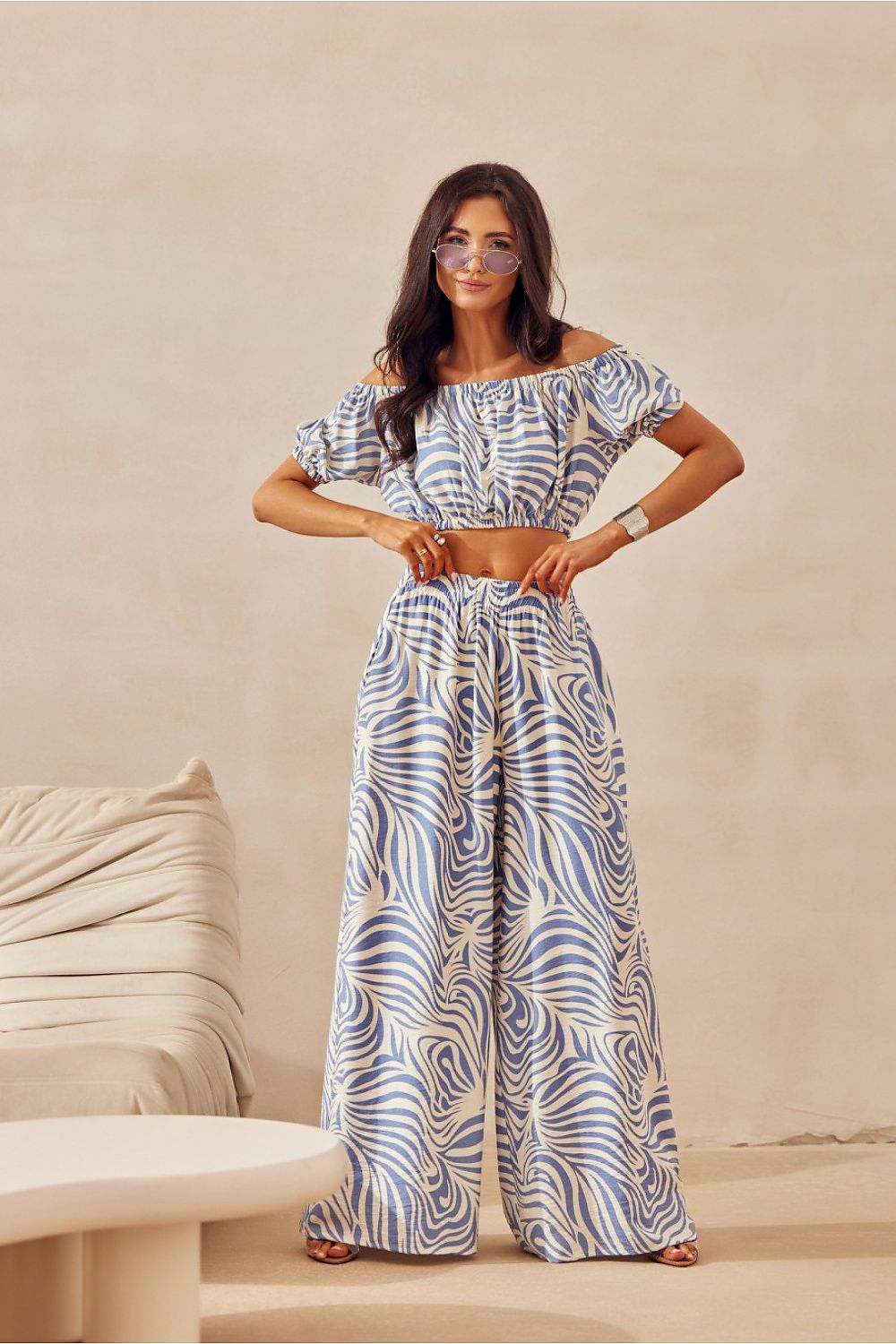 Woman wearing a patterned outfit standing against a beige background