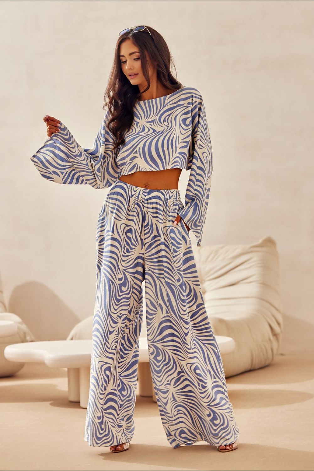 Woman wearing a blue and white patterned outfit in a minimalistic room.