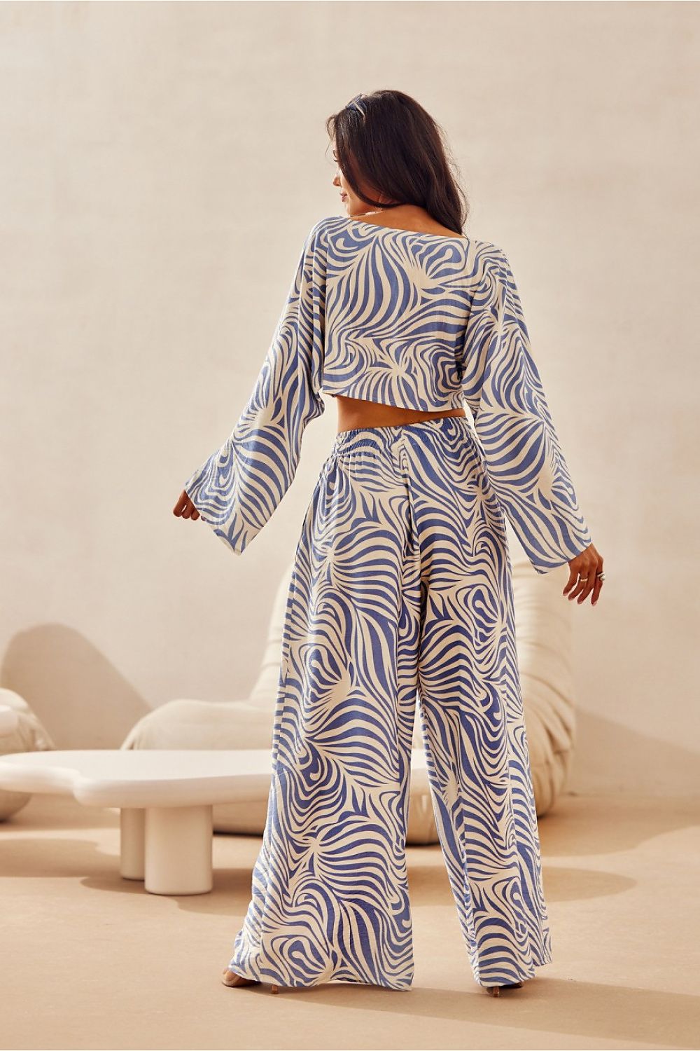 Woman wearing a blue and white patterned outfit in a minimalistic setting
