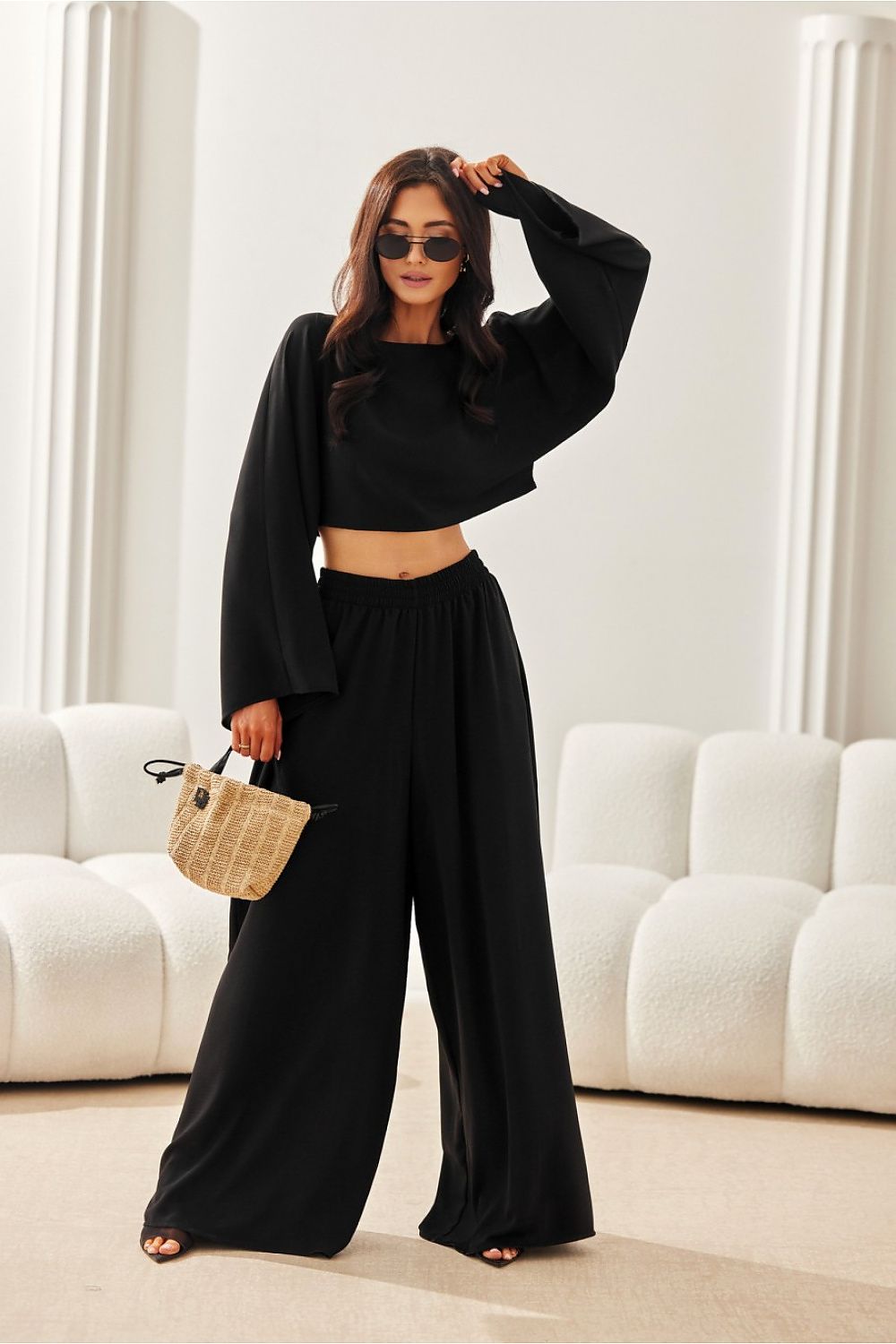 Woman in a black outfit standing in a room with white furniture