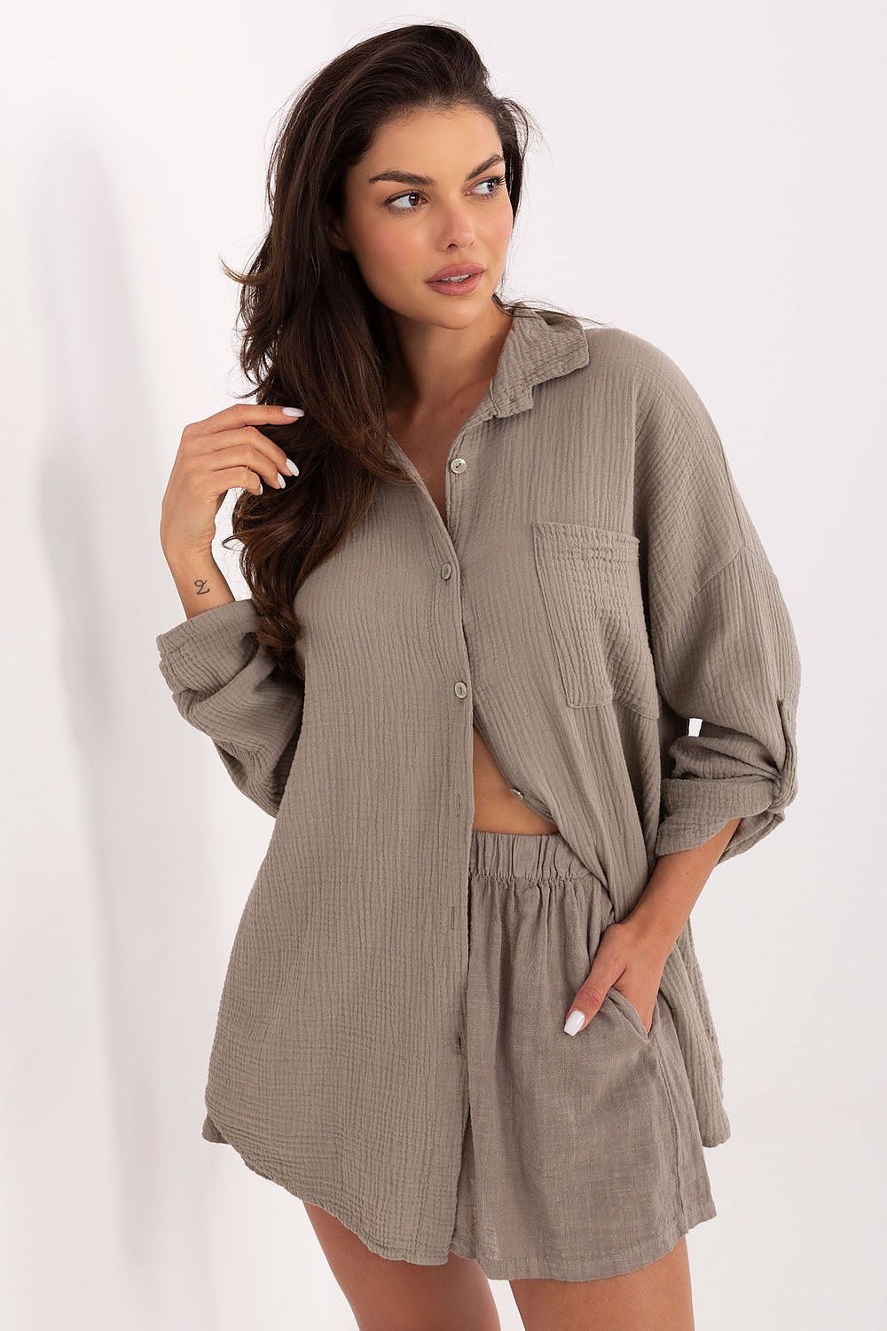 Woman wearing a matching brown shirt and shorts set on a white background