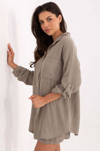 Woman wearing a long, light brown shirt against a white background