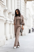 Woman in a beige outfit walking on a city street.