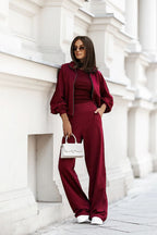 Woman in a burgundy outfit standing against a white architectural background