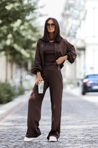 Woman in a brown outfit holding a Starbucks cup on a street.