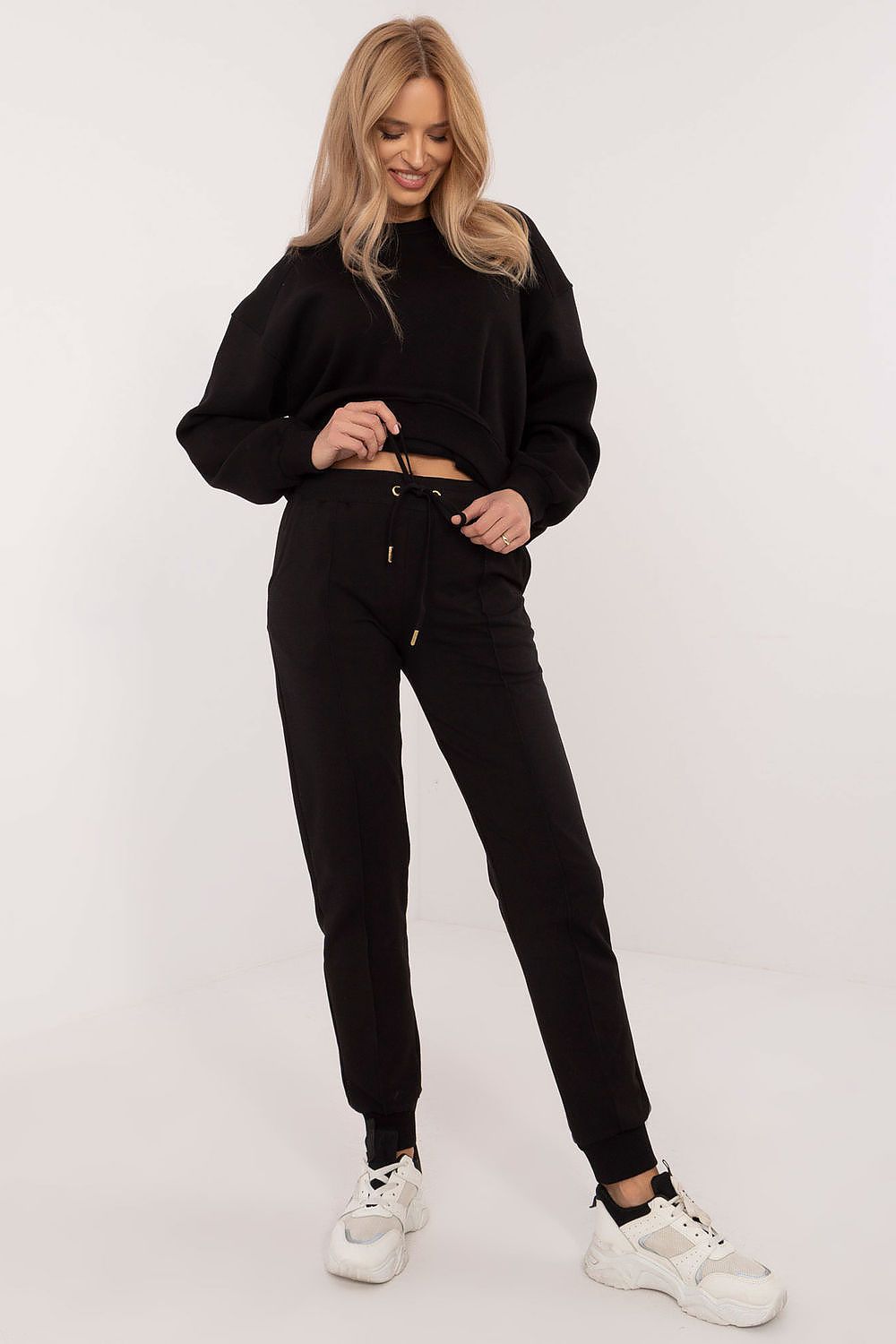 Woman wearing a black outfit with white sneakers on a white background