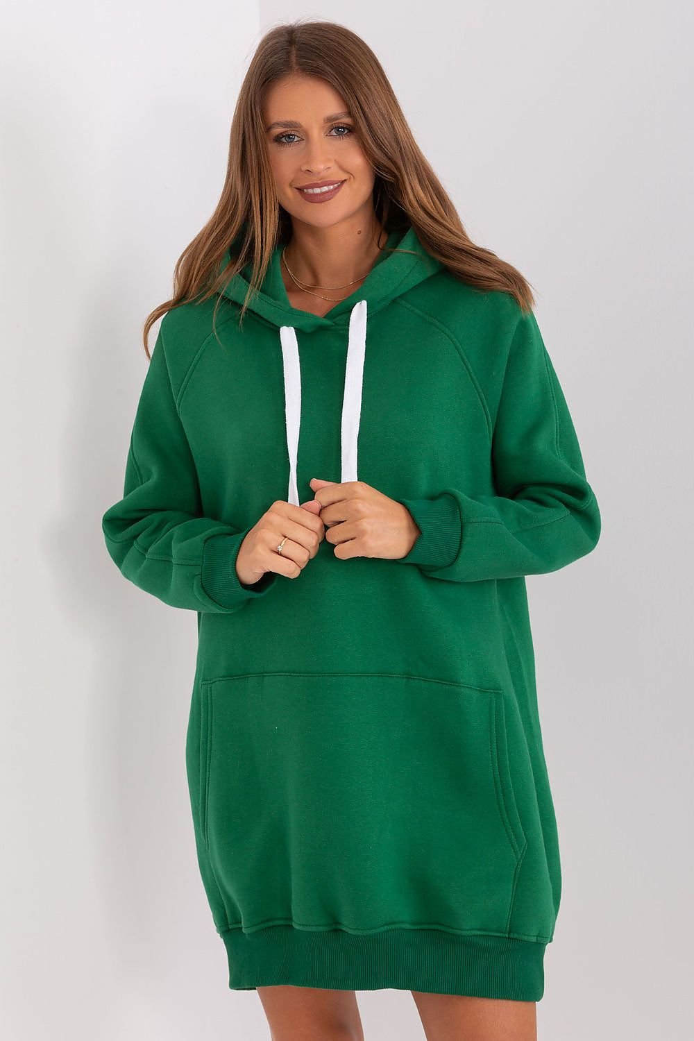 Woman wearing a green hoodie against a white background