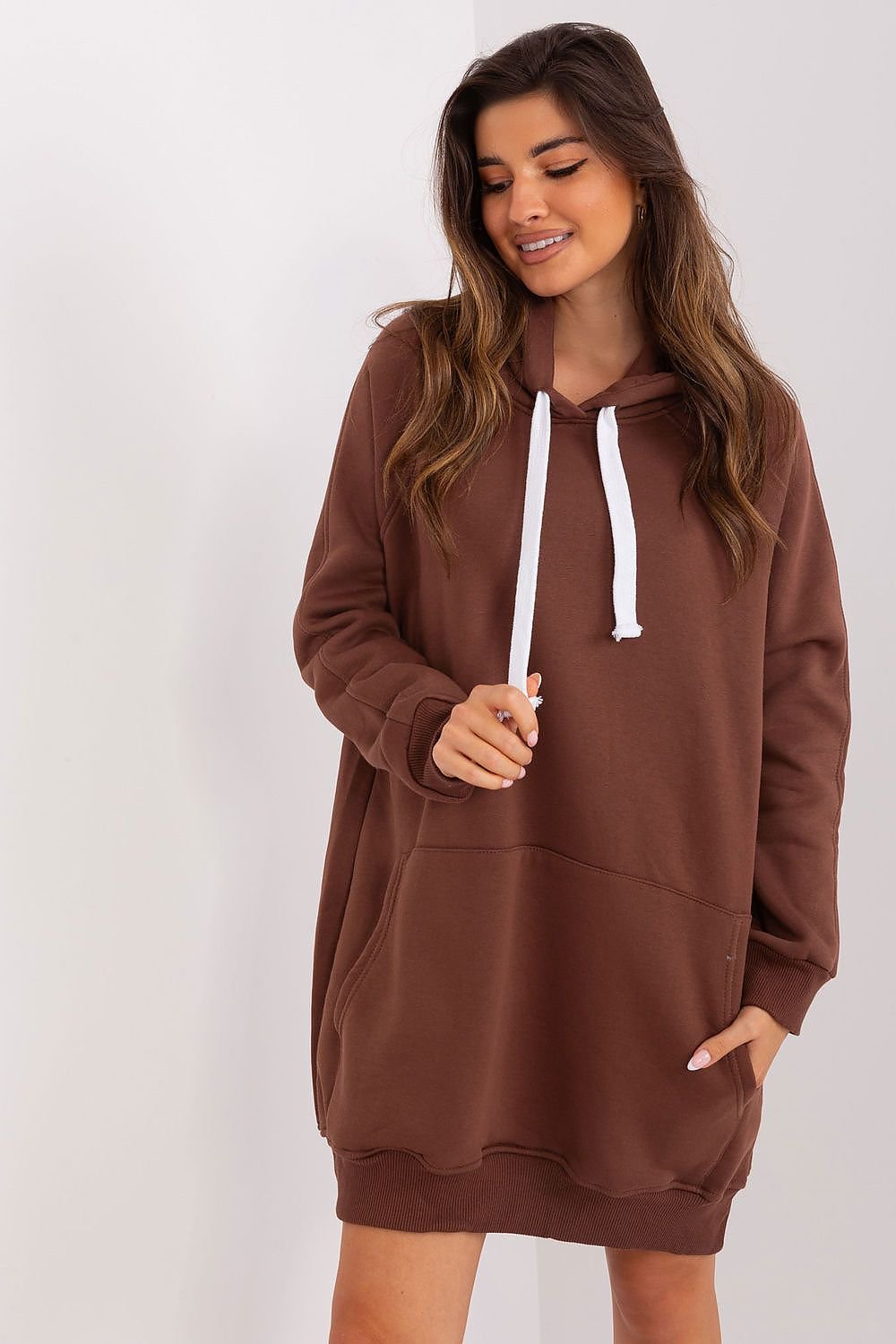 Woman wearing a brown hoodie dress against a white background