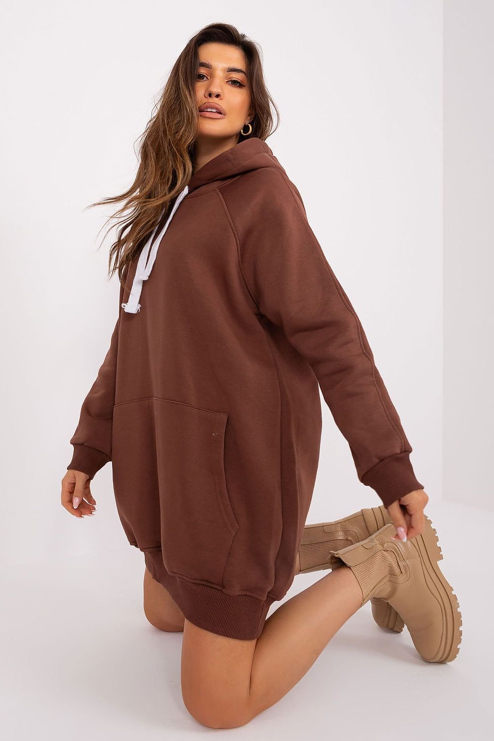 Woman wearing a brown hoodie and beige boots on a white background