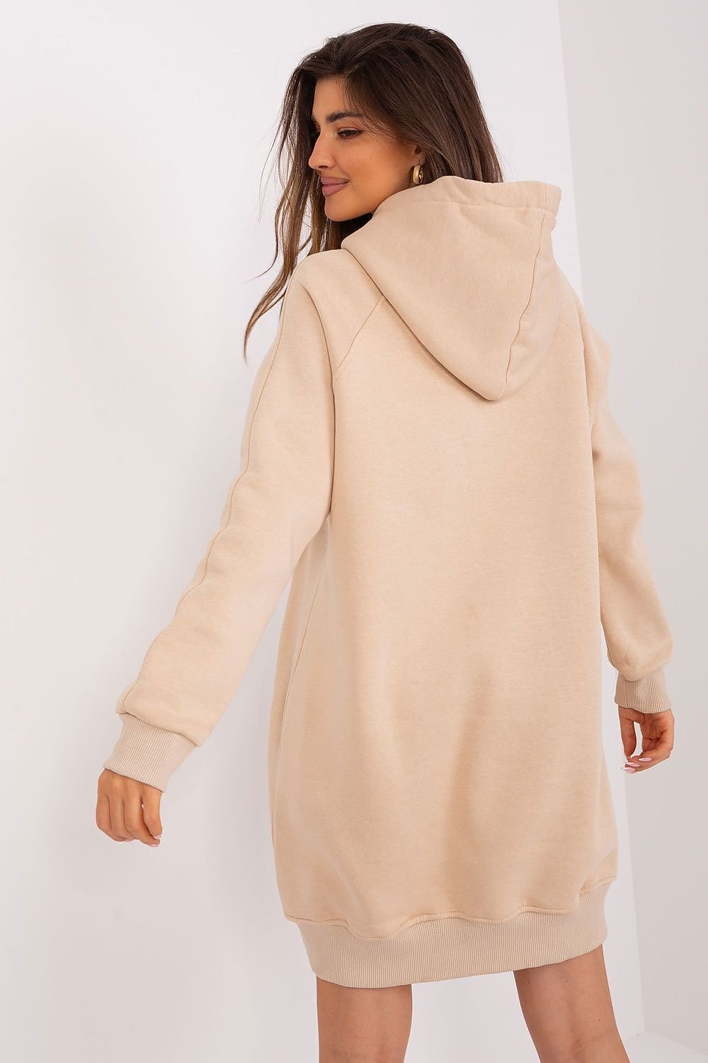 Woman wearing a beige hoodie dress against a white background