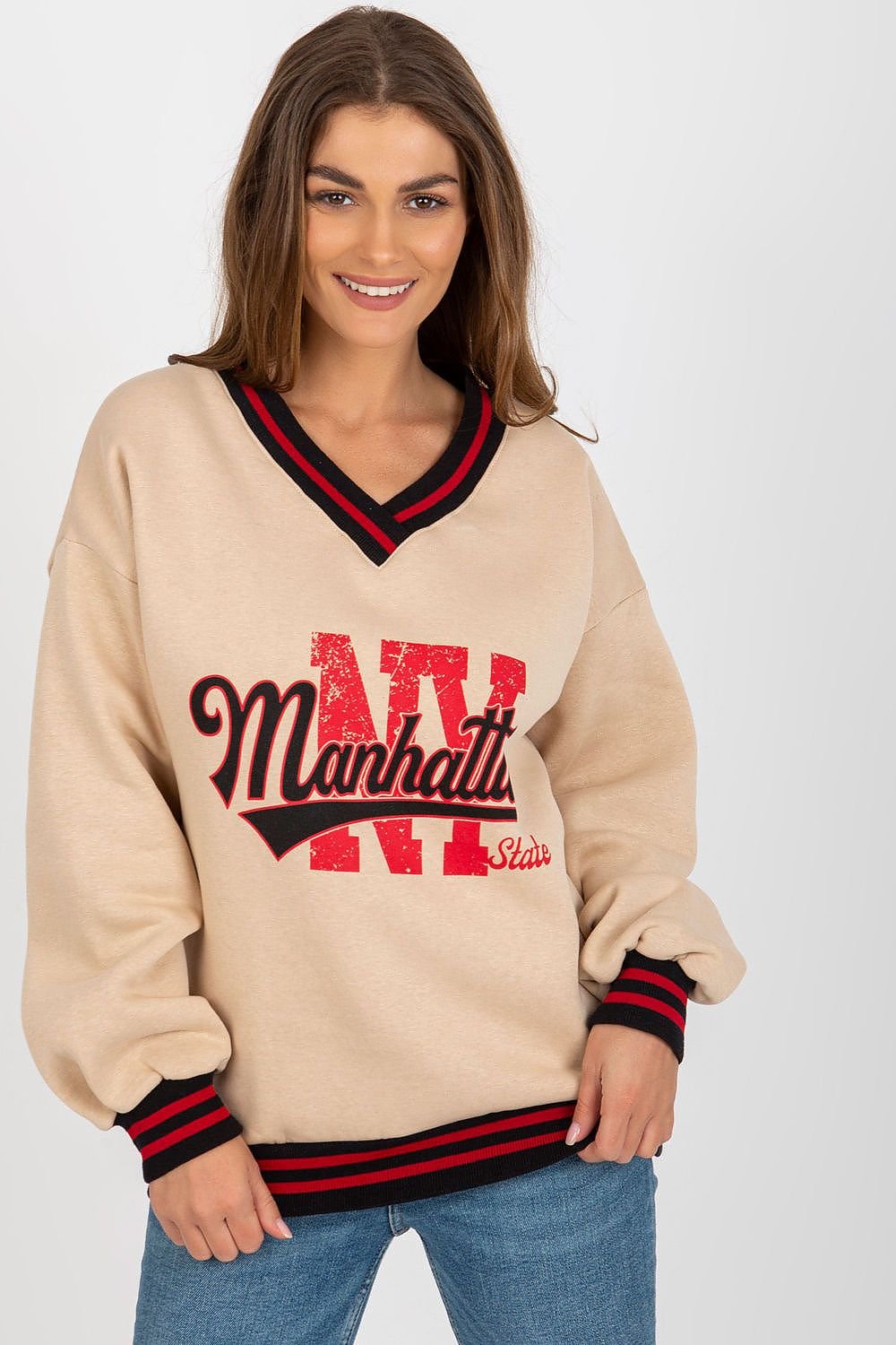 Woman wearing a beige sweater with red and black text and trim on a white background