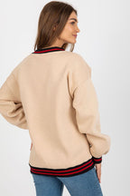 Woman wearing a beige sweater with red and black stripes on a white background