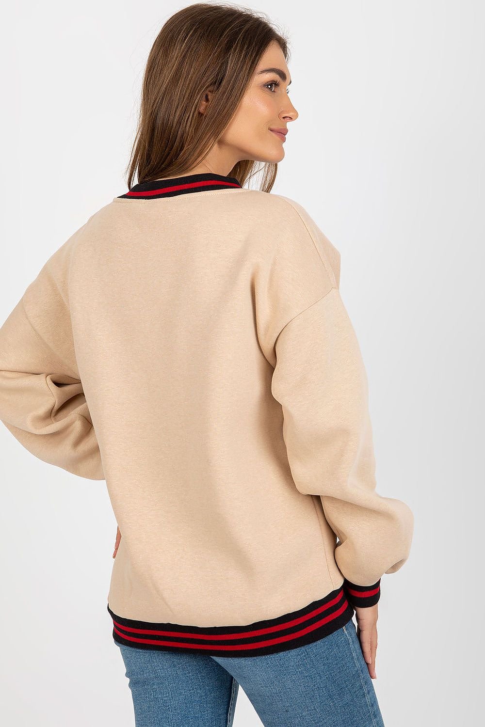 Woman wearing a beige sweater with red and black stripes on a white background
