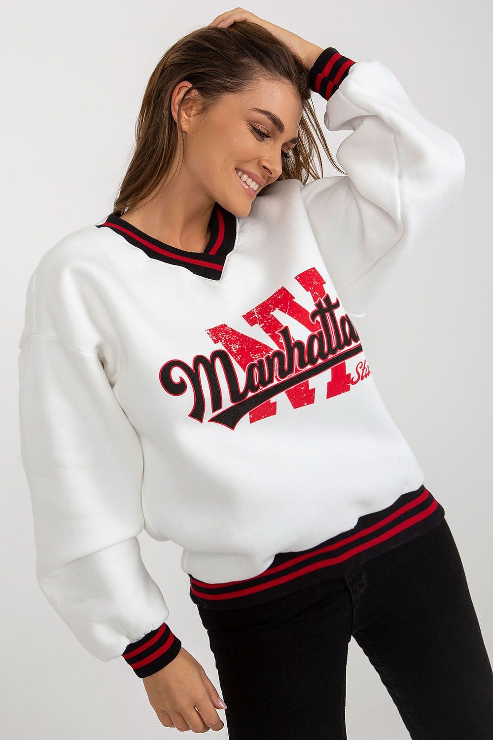 Woman wearing a white sweatshirt with red and black text on a plain background