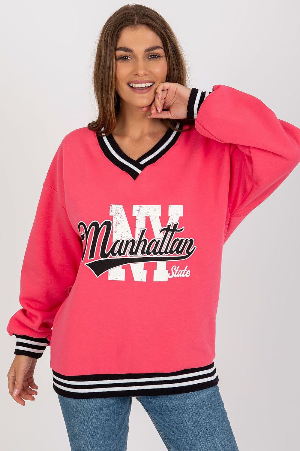 Woman wearing a pink sweatshirt with 'Manhattan State' text on a plain background