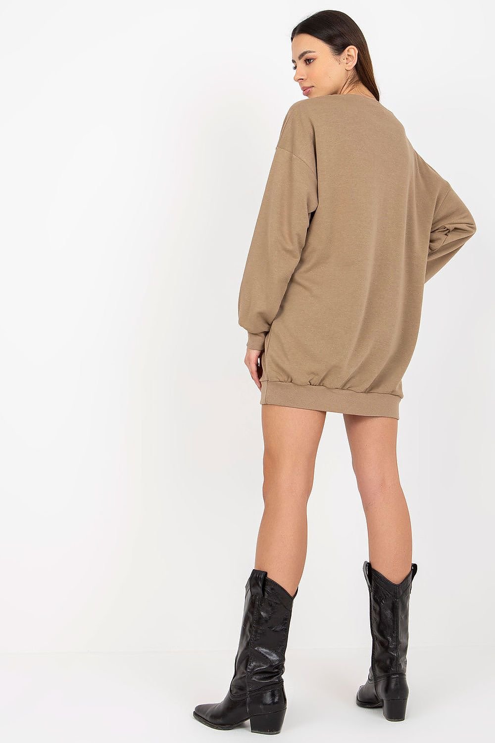 Person wearing a beige sweatshirt dress and black boots on a white background