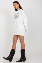 Woman wearing a white oversized sweatshirt with text and black cowboy boots on a white background
