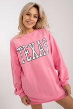 Woman wearing a pink sweatshirt with 'TEXAS' printed on it against a white background