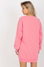 Woman wearing a pink sweatshirt dress against a white background