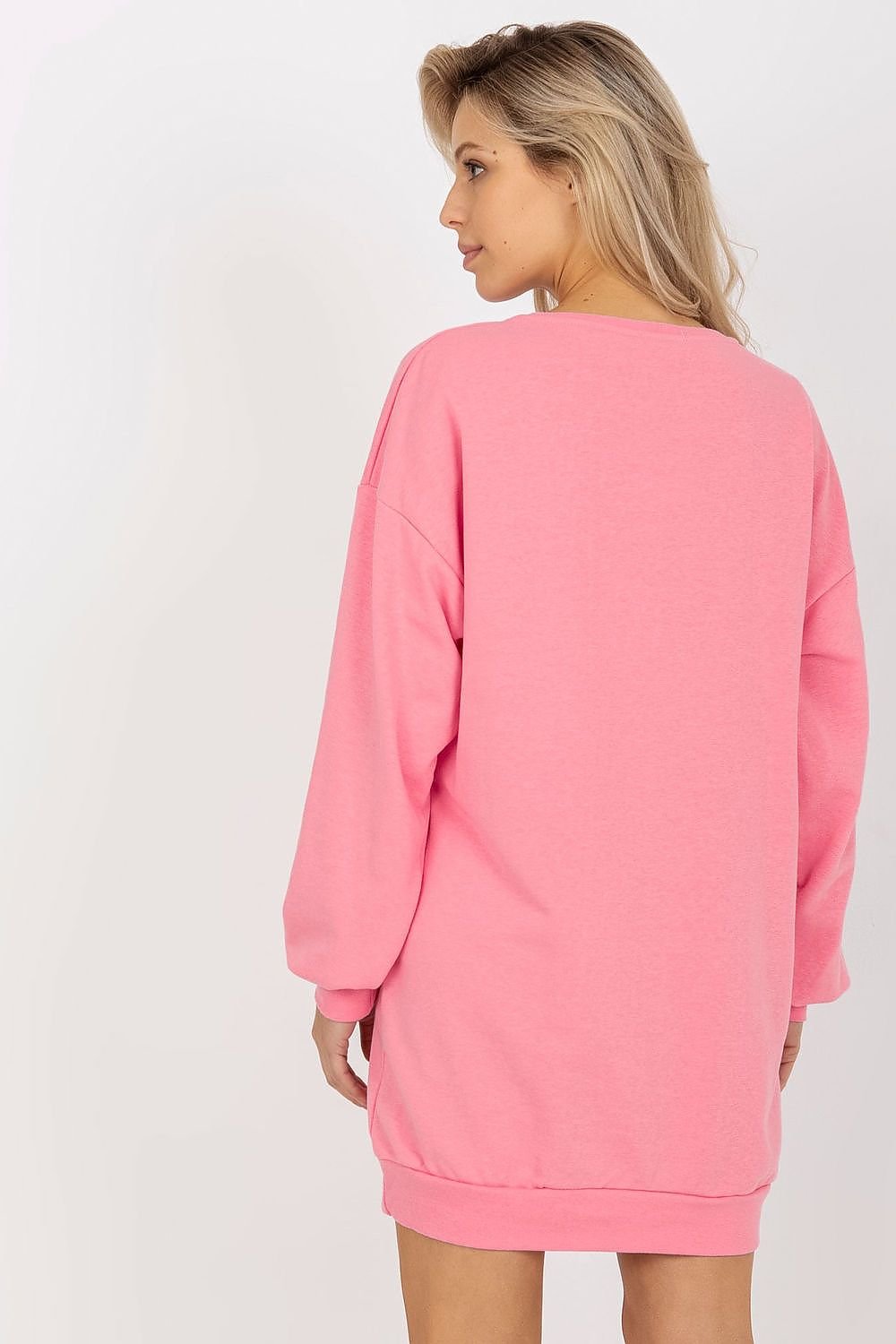 Woman wearing a pink sweatshirt dress against a white background