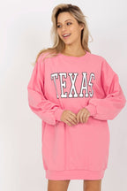 Woman wearing a pink 'TEXAS' sweatshirt dress on a white background