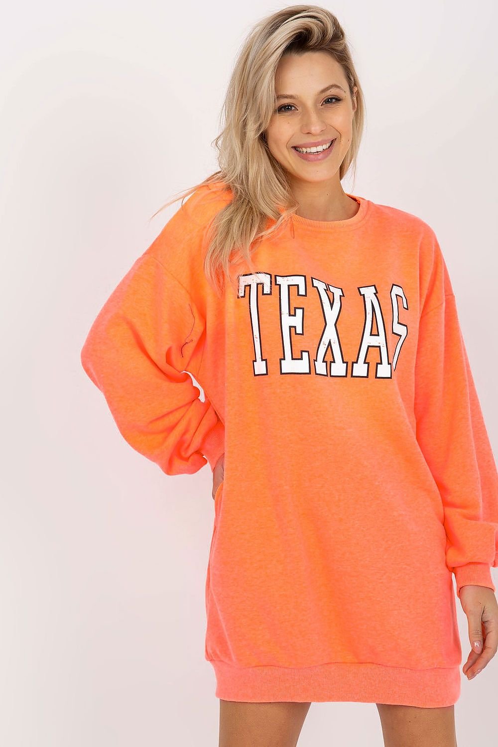 Woman wearing a bright orange sweatshirt with 'TEXAS' printed on it against a white background