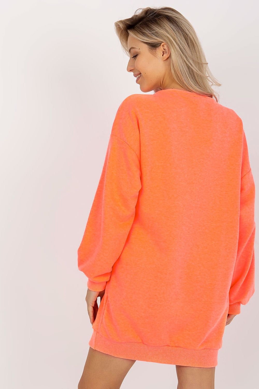 Woman wearing a bright orange dress against a plain background