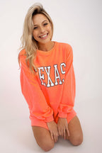 Woman wearing a bright orange sweatshirt with 'TEXAS' printed on it against a white background