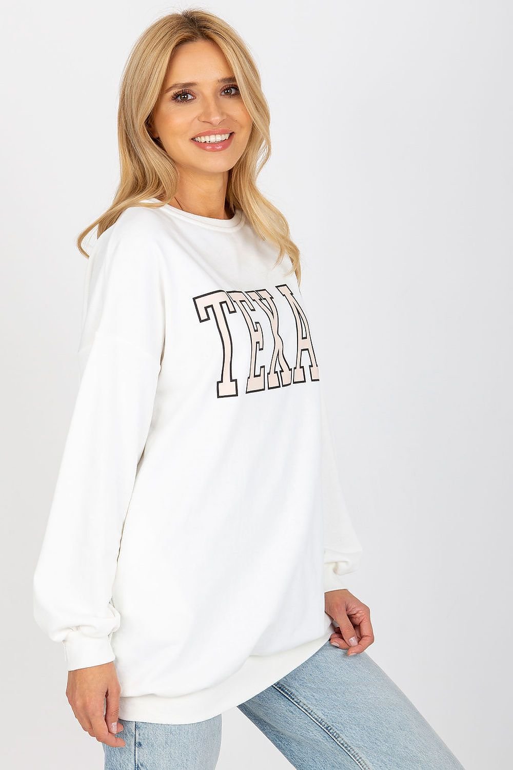 Woman wearing a white sweatshirt with 'TEXA' text on a plain background